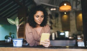 Caucasian woman reading content publication while performing due diligence via social media on smartphone