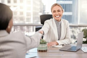 Woman smiling after due diligence saves her deal, shaking a woman's hand